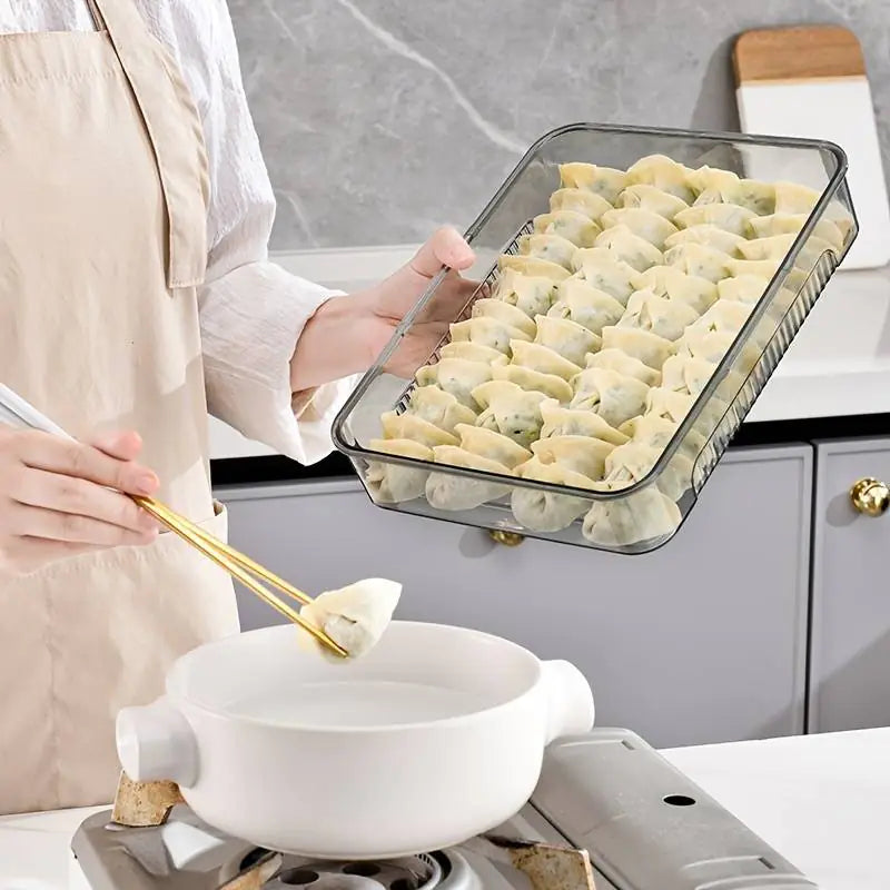 Person preparing dumplings in a glass dish with a white pot on a stove.