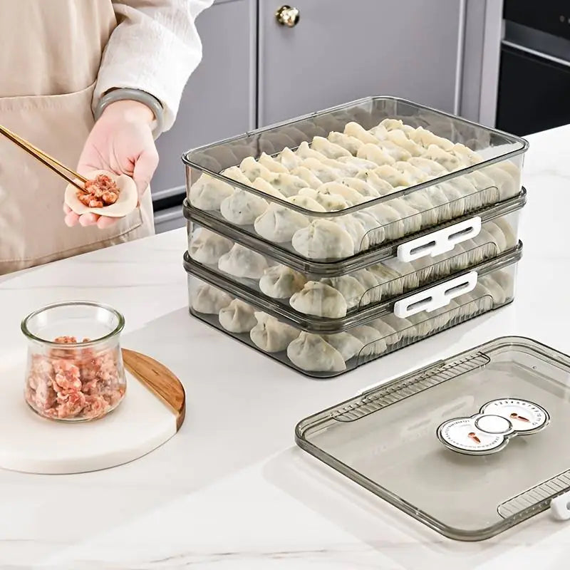 Stackable clear containers with dumplings on a kitchen counter.